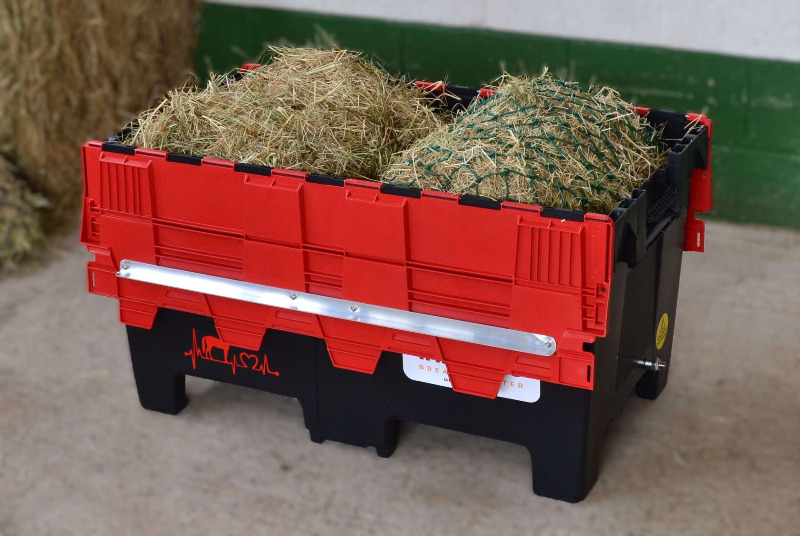 a red and black plastic container with hay in it